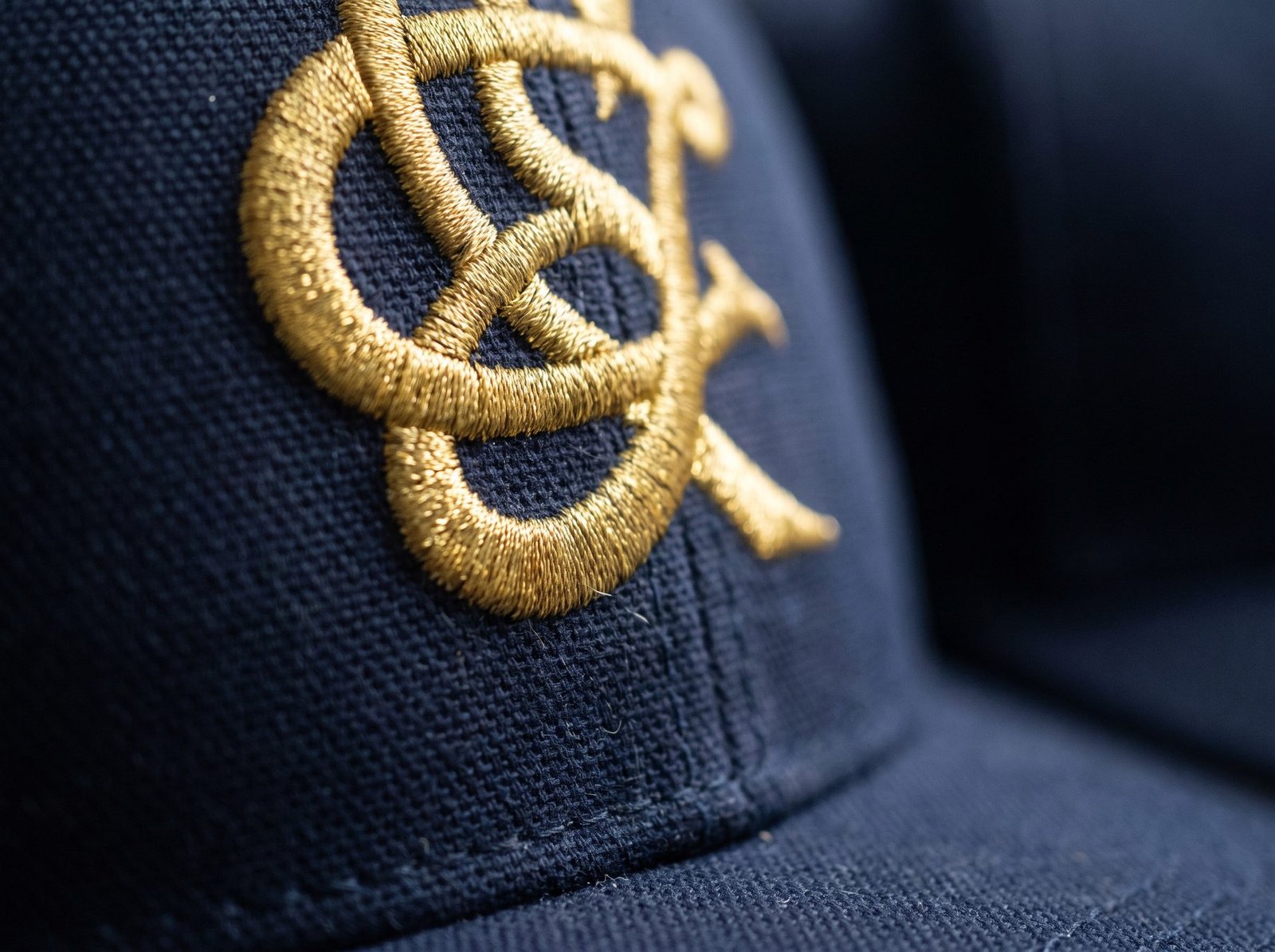 Extreme close-up of an embroidered structured baseball cap with gold thread stitching